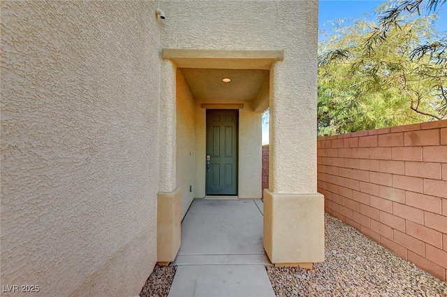 doorway to property with fence and stucco siding