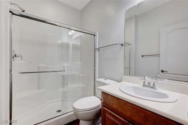 bathroom featuring toilet, a shower stall, and vanity