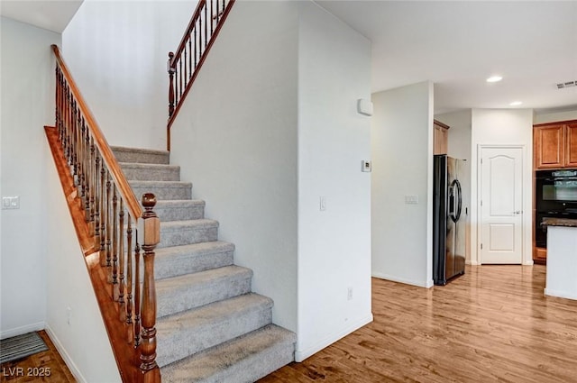 stairway featuring visible vents, baseboards, wood finished floors, and recessed lighting