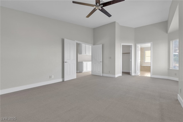 unfurnished bedroom with a walk in closet, light carpet, a closet, ceiling fan, and connected bathroom