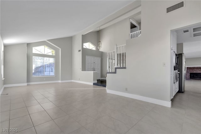 unfurnished living room featuring high vaulted ceiling, light tile patterned floors, and a fireplace