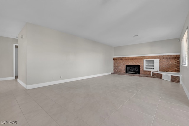 unfurnished living room with a brick fireplace, light tile patterned floors, and built in features