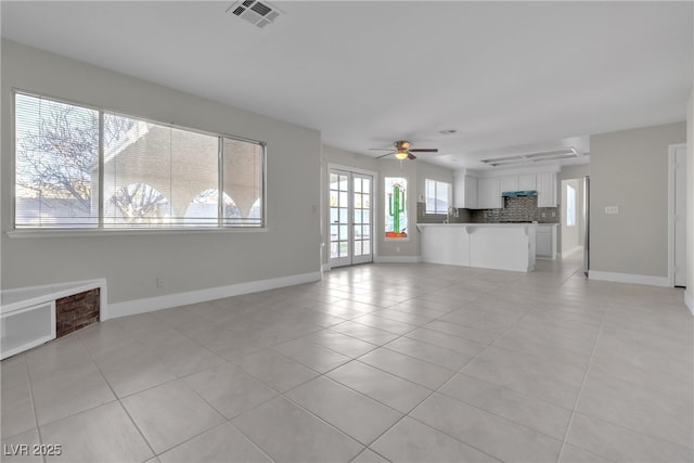 unfurnished living room featuring ceiling fan, sink, and light tile patterned floors