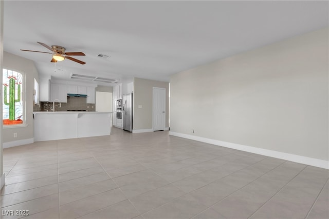 unfurnished living room with sink, ceiling fan, and light tile patterned floors