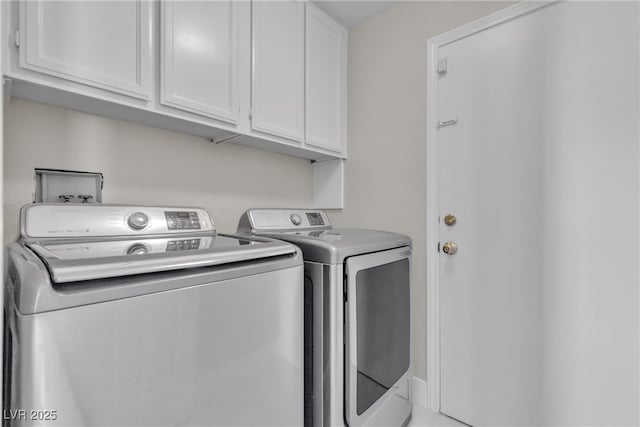 clothes washing area featuring cabinets and washing machine and clothes dryer