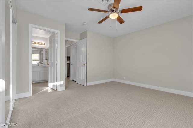 unfurnished bedroom with light colored carpet, ensuite bath, and ceiling fan