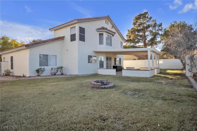 back of house featuring an outdoor fire pit and a yard