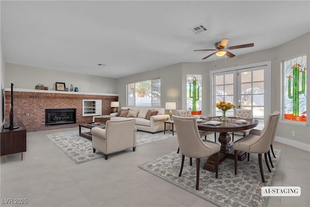 dining area with ceiling fan, french doors, and a fireplace