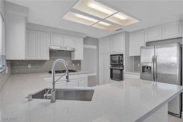 kitchen with kitchen peninsula, sink, white cabinets, black appliances, and decorative backsplash