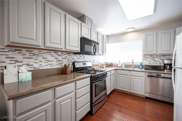 kitchen with appliances with stainless steel finishes, dark hardwood / wood-style flooring, sink, dark stone countertops, and white cabinets