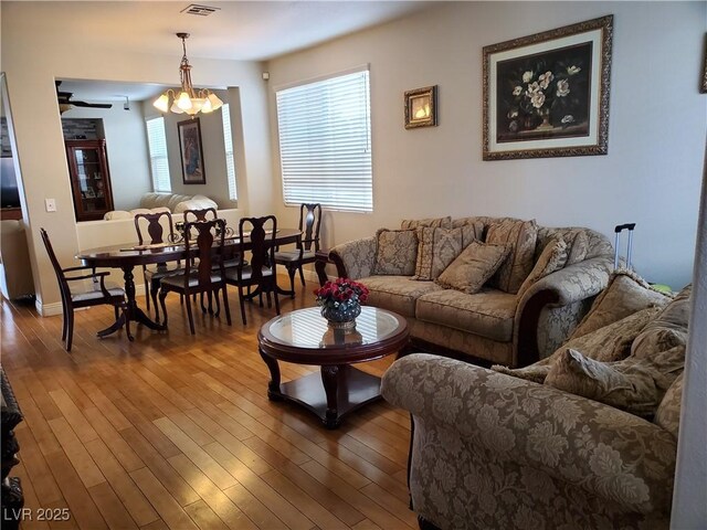 living room featuring dark wood-type flooring and ceiling fan with notable chandelier