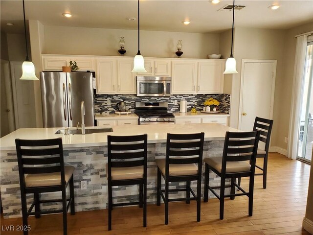 kitchen featuring white cabinetry, sink, a kitchen breakfast bar, stainless steel appliances, and a center island with sink