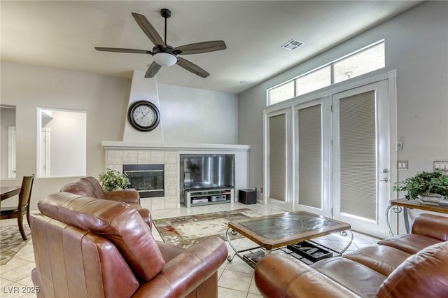 tiled living room with ceiling fan and a tiled fireplace