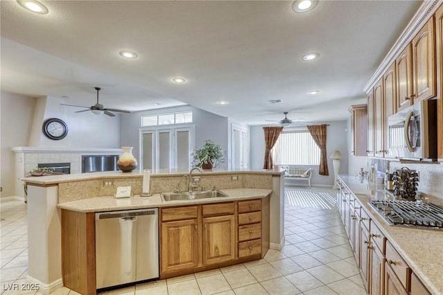 kitchen with appliances with stainless steel finishes, tasteful backsplash, sink, light tile patterned floors, and a tile fireplace