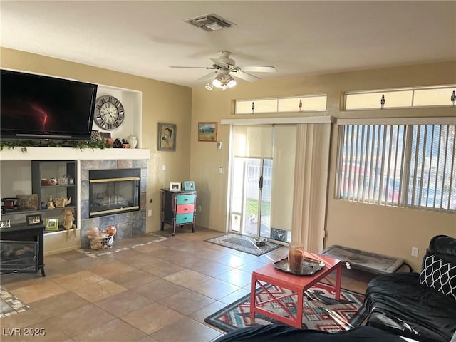 living room with ceiling fan, tile patterned flooring, and a tile fireplace