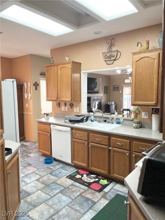 kitchen with white appliances, kitchen peninsula, and sink