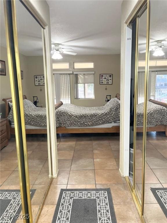 bedroom with ceiling fan, tile patterned flooring, and two closets