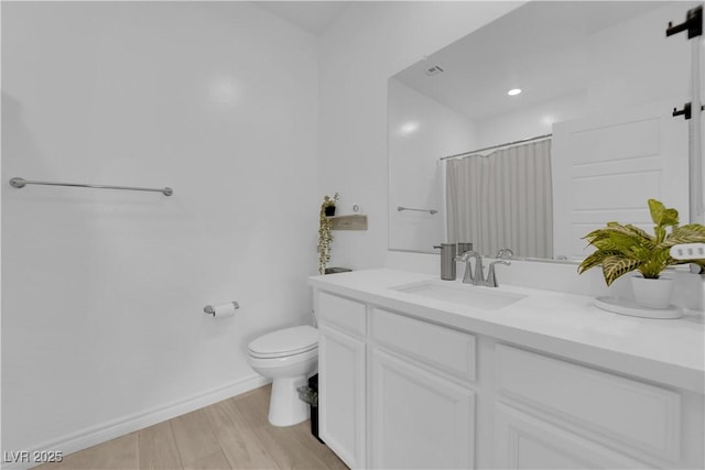 bathroom with hardwood / wood-style floors, vanity, toilet, and curtained shower