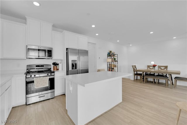 kitchen featuring a kitchen island, light wood-type flooring, white cabinetry, and stainless steel appliances