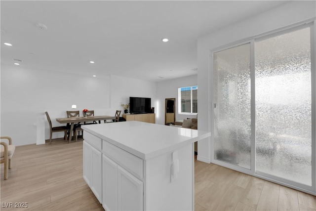 kitchen with white cabinets, a kitchen island, and light wood-type flooring