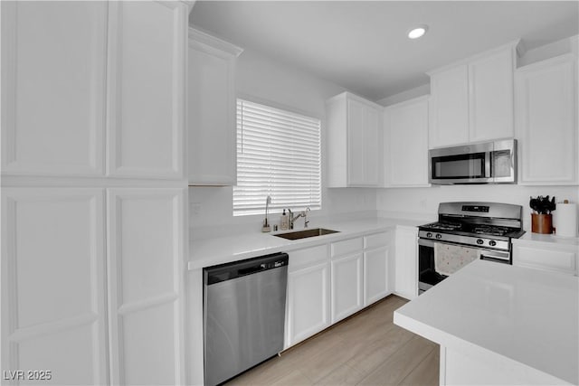 kitchen featuring sink, white cabinets, light hardwood / wood-style floors, and appliances with stainless steel finishes