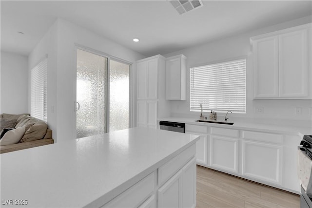 kitchen with white cabinets, light hardwood / wood-style floors, a wealth of natural light, and sink