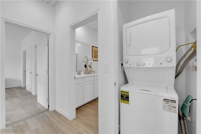 laundry area featuring stacked washing maching and dryer and sink