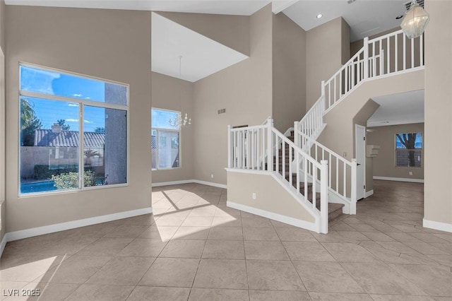 foyer entrance with light tile patterned floors, a towering ceiling, and an inviting chandelier