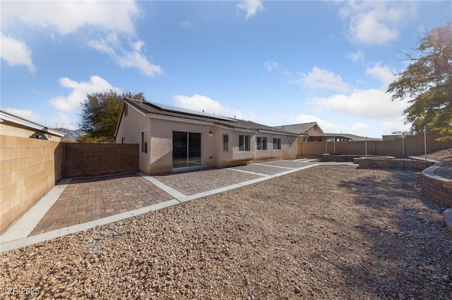 rear view of house featuring a patio and solar panels