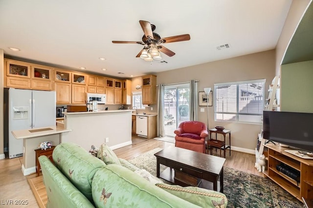 living room with light hardwood / wood-style flooring, ceiling fan, and sink