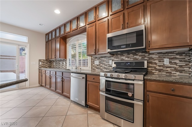 kitchen with plenty of natural light, decorative backsplash, light tile patterned floors, and stainless steel appliances