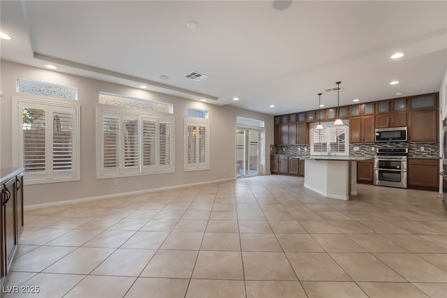 kitchen featuring pendant lighting, a kitchen island, light tile patterned floors, and appliances with stainless steel finishes