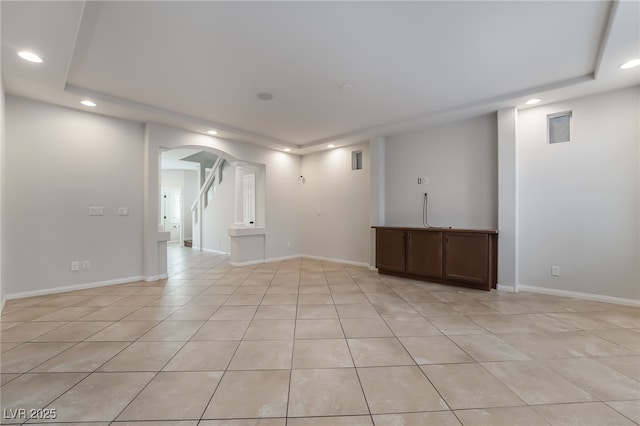 empty room with light tile patterned flooring and a tray ceiling