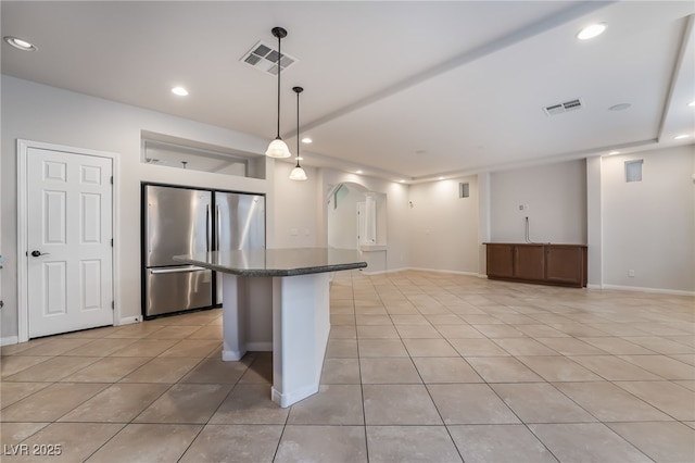 kitchen featuring stainless steel refrigerator, a center island, decorative light fixtures, a breakfast bar, and light tile patterned floors