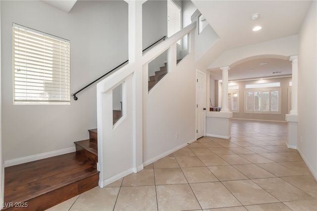 staircase featuring tile patterned floors, a wealth of natural light, and decorative columns