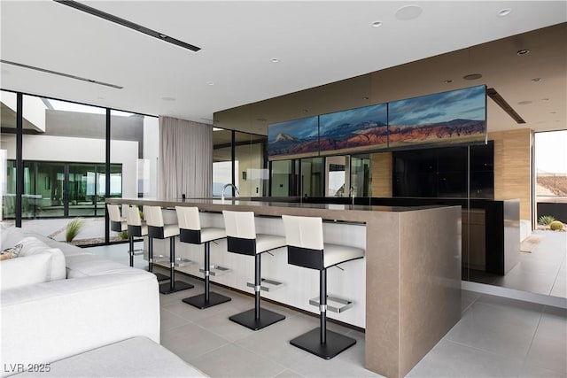 interior space featuring expansive windows, light tile patterned floors, and sink