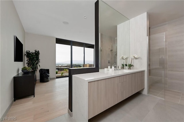 bathroom with a tile shower, vanity, floor to ceiling windows, and hardwood / wood-style floors