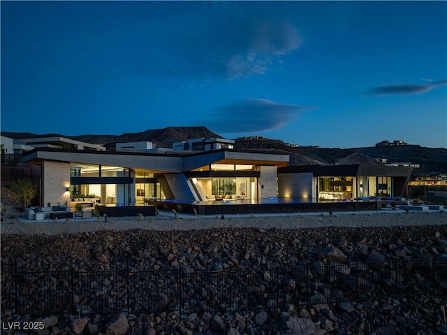 back house at dusk featuring a mountain view and an outdoor living space