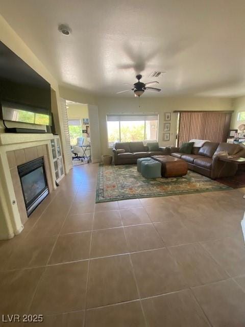 unfurnished living room featuring a tile fireplace, ceiling fan, and tile patterned flooring