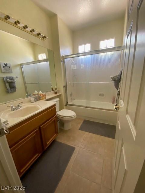 full bathroom featuring shower / bath combination with glass door, vanity, tile patterned flooring, and toilet