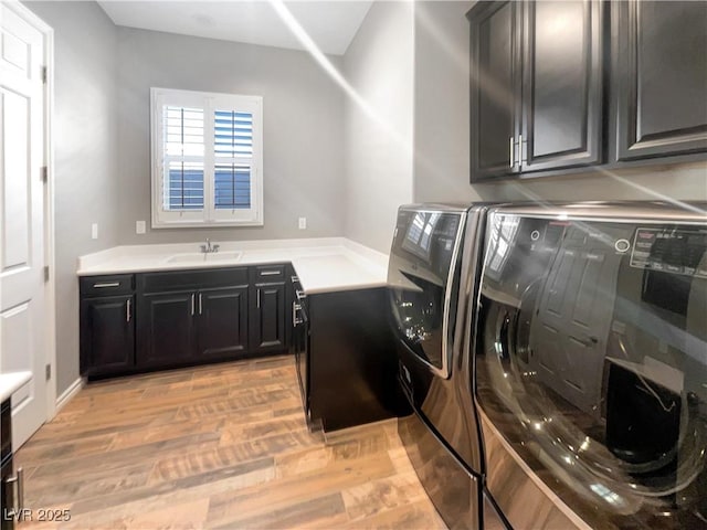 washroom featuring cabinets, light hardwood / wood-style floors, and washing machine and clothes dryer