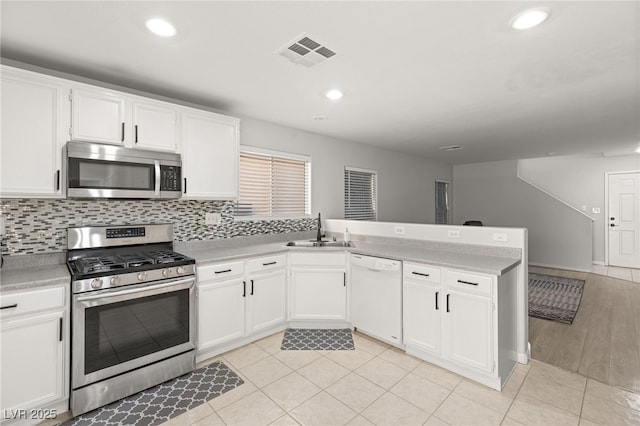 kitchen featuring white cabinetry, sink, stainless steel appliances, backsplash, and kitchen peninsula