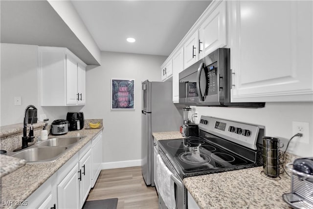 kitchen featuring light stone counters, stainless steel appliances, sink, light hardwood / wood-style flooring, and white cabinets