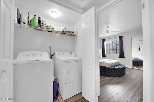 washroom with ceiling fan, hardwood / wood-style floors, washer and dryer, and a textured ceiling