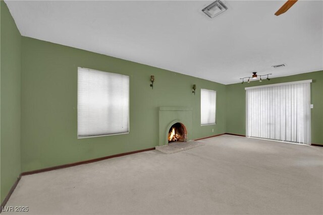 unfurnished living room featuring light carpet, ceiling fan, and a healthy amount of sunlight