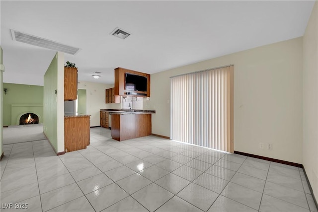 kitchen featuring kitchen peninsula, sink, and light tile patterned flooring