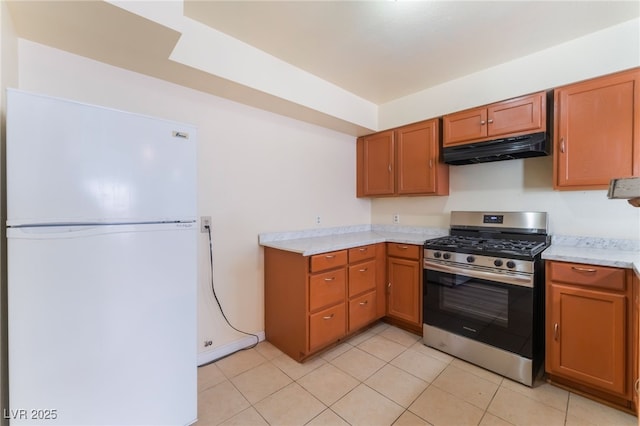 kitchen with light tile patterned flooring, white refrigerator, and stainless steel gas stove