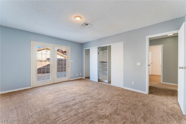 unfurnished bedroom featuring a textured ceiling, light carpet, and french doors