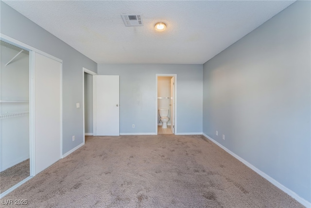 unfurnished bedroom with light colored carpet, connected bathroom, and a textured ceiling