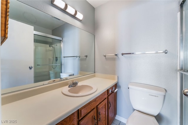 bathroom with toilet, vanity, and a shower with door